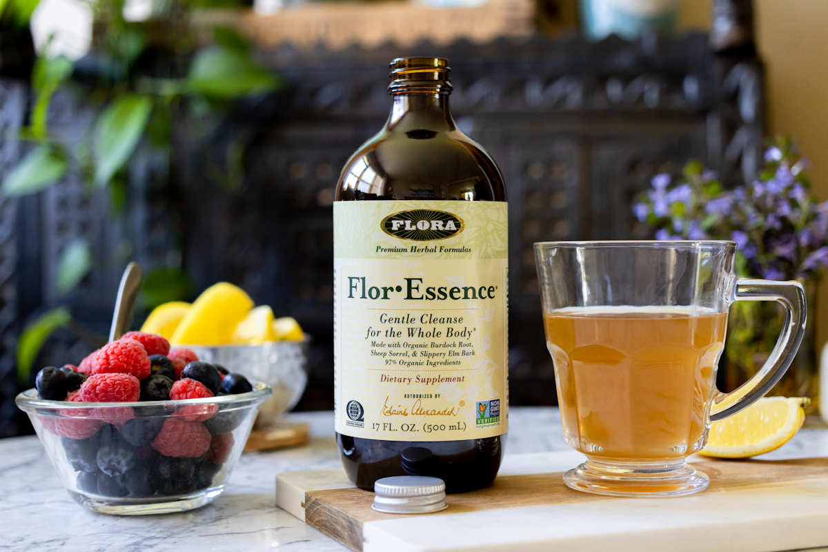 Flora For-Essence on a table with a mug of tea and fresh fruit