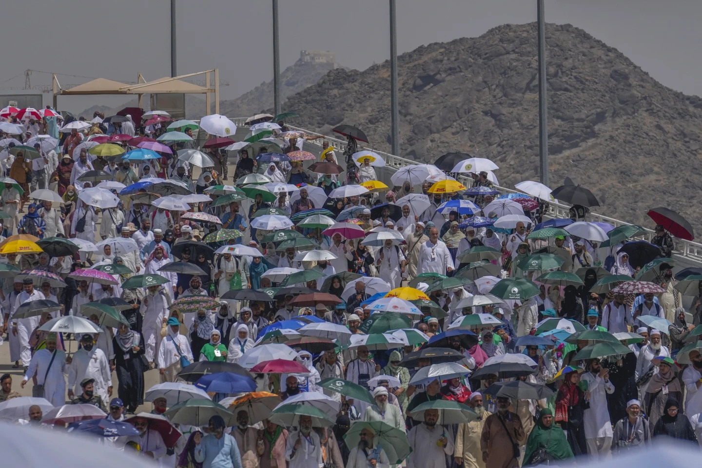 Muslim pilgrims use umbrellas to shield themselves from the sun as they arrive to cast stones at pillars in the symbolic stoning of the devil, the last rite of the annual Hajj, in Mina, near the holy city of Mecca, Saudi Arabia, Tuesday, June 18, 2024. (AP Photo/Rafiq Maqbool)