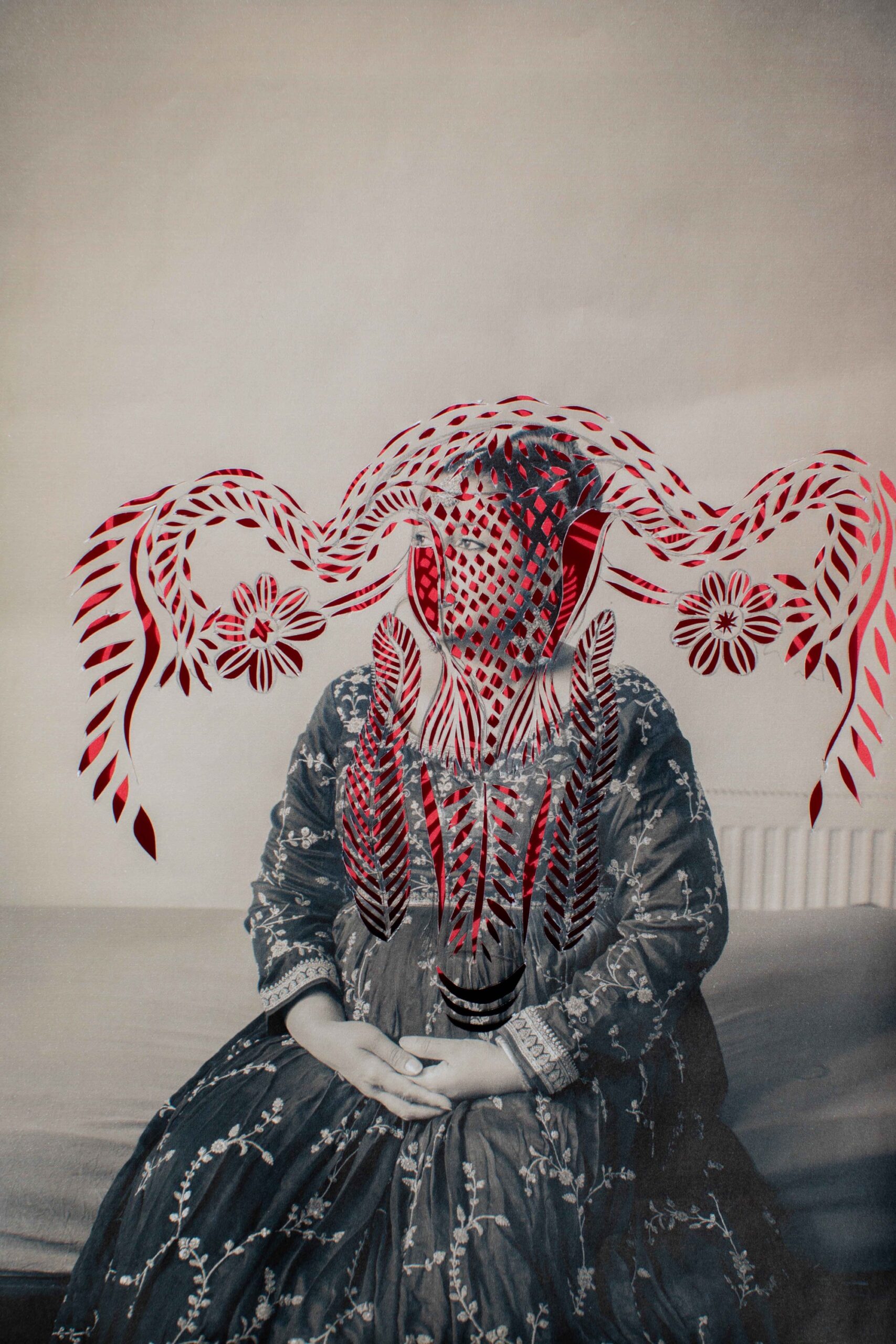 a black-and-white photograph of an anonymous south Asian woman that has been cut with a pattern in the outline of a uterus, with red paper shows through from the back