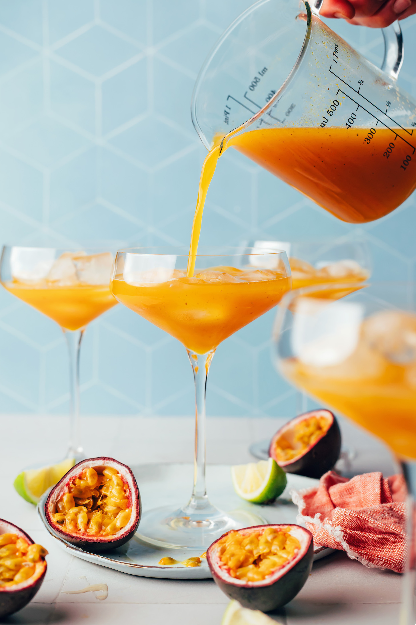 Pouring our spicy passion fruit mocktail recipe from a measuring glass into a serving glass