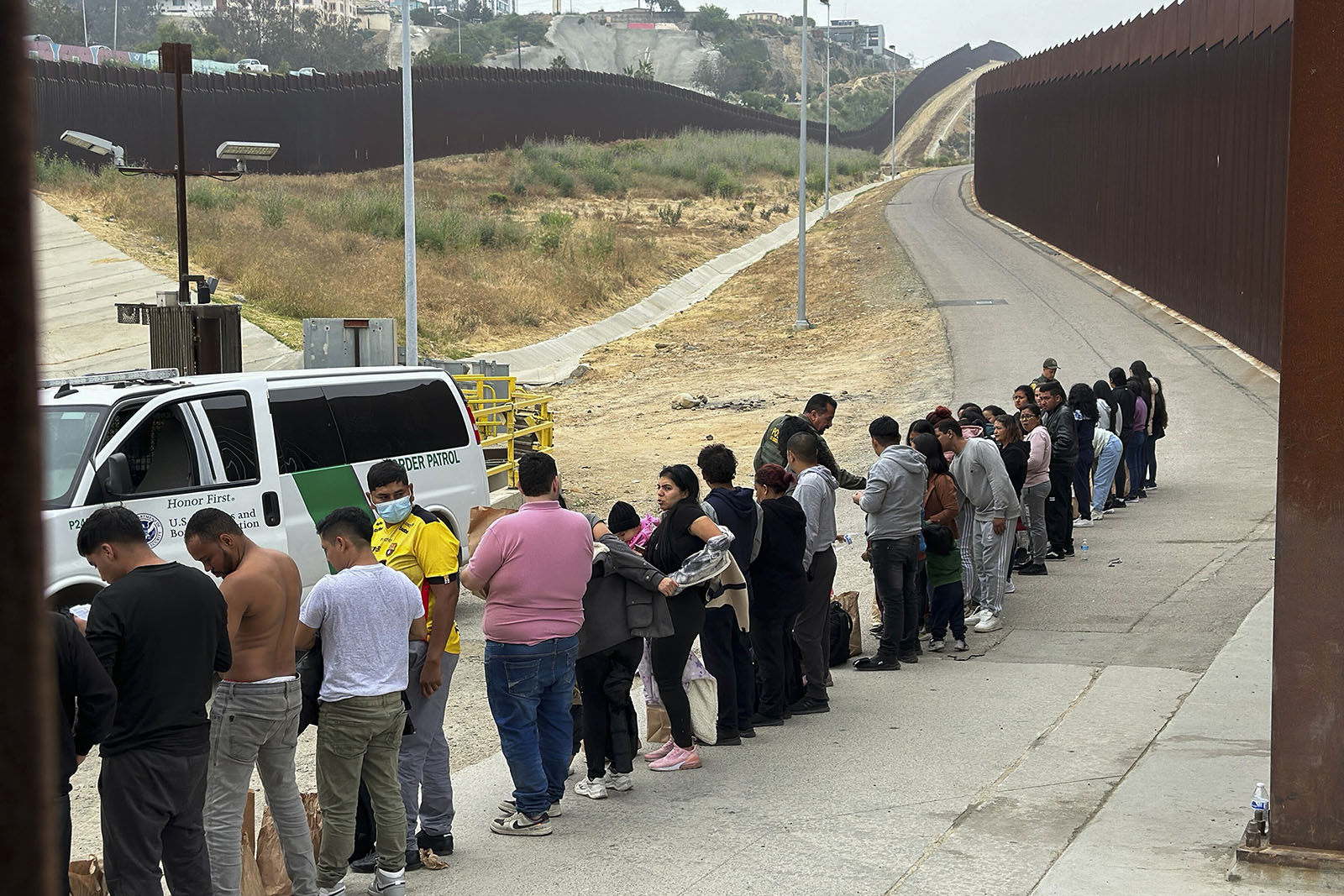 Migrants seeking asylum line up while waiting to be processed after crossing the border Wednesday, June 5, 2024, near San Diego, Calif.  (AP Photo/Eugene Garcia)