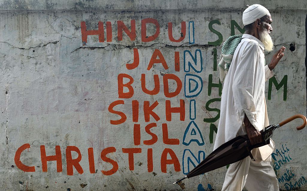 An Indian man walks past a wall graffiti on various religions in Mumbai on June 25, 2015. AFP PHOTO/ Indranil MUKHERJEE        (Photo credit should read INDRANIL MUKHERJEE/AFP/Getty Images)