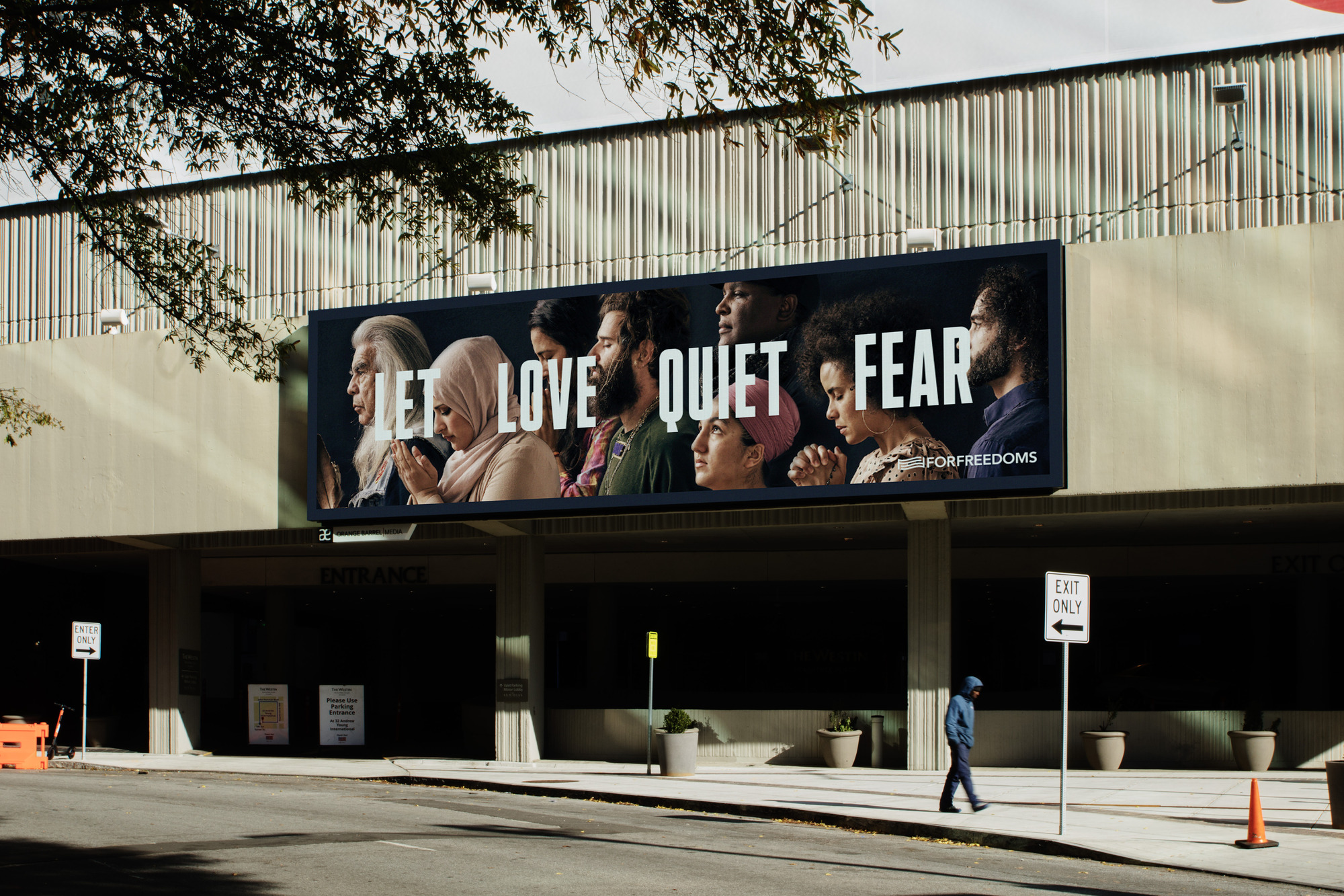 a billboard with a photo of a diverse group of individuals from different walks of life reading, "LET LOVE QUIET FEAR"