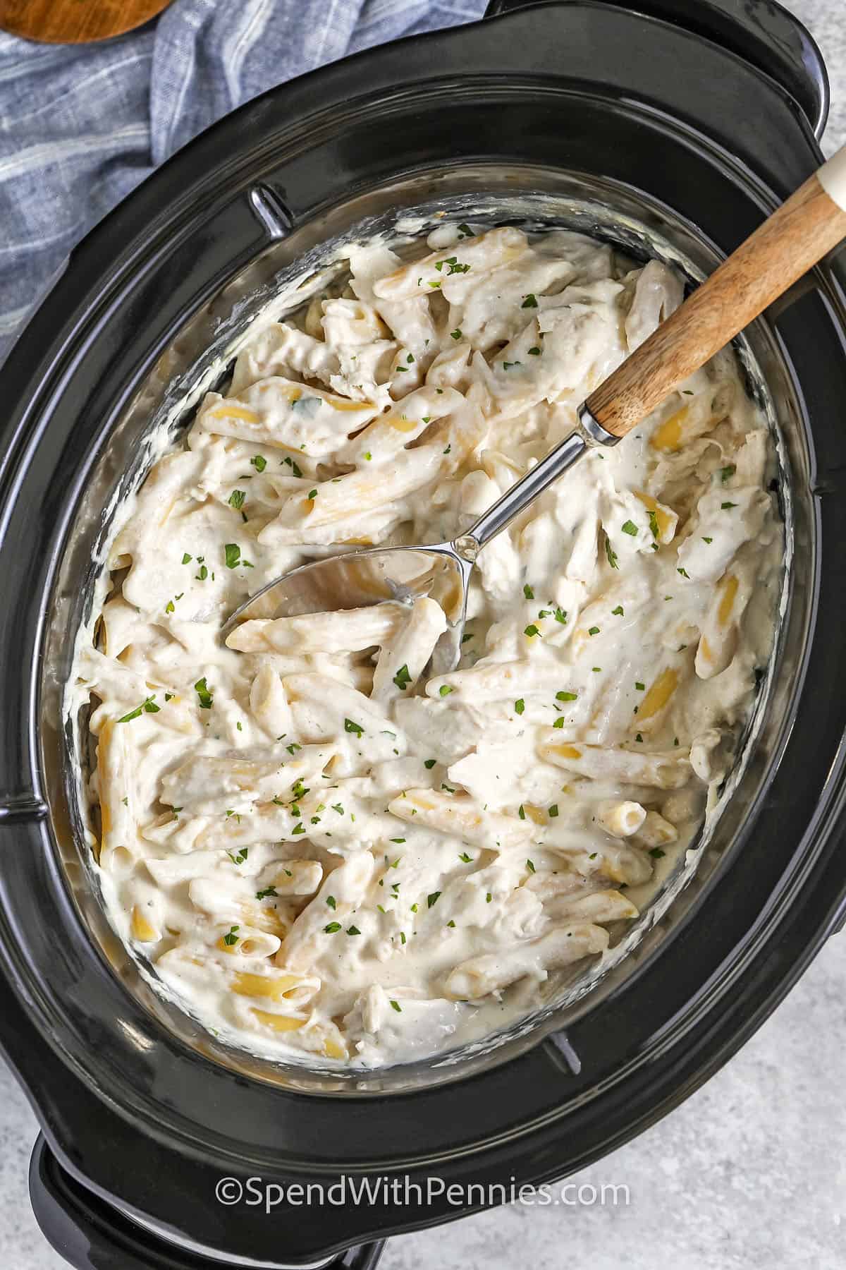 pot of Crock Pot Chicken Alfredo with a spoon