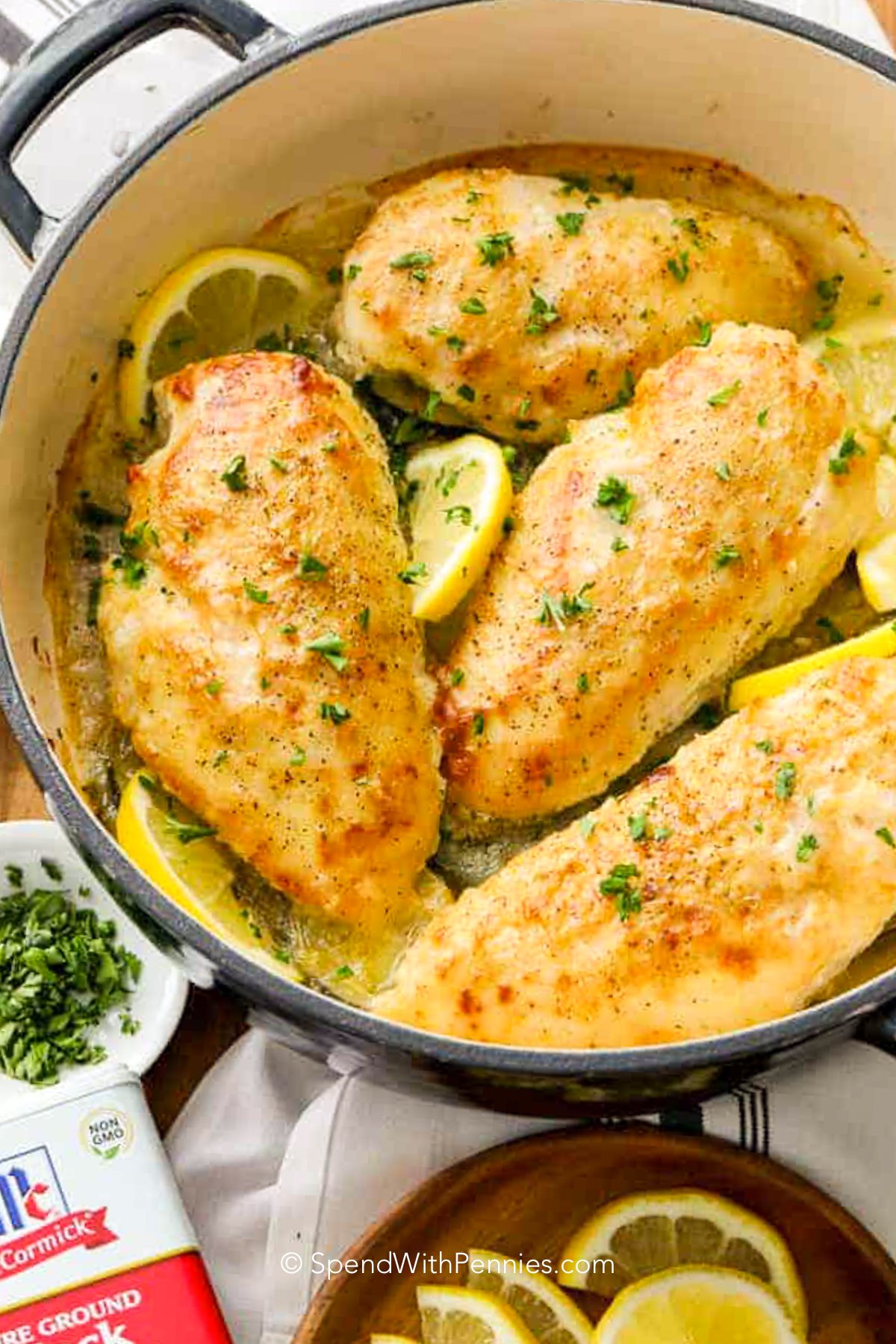 a dutch oven with lemon pepper chicken breasts and slices of lemon