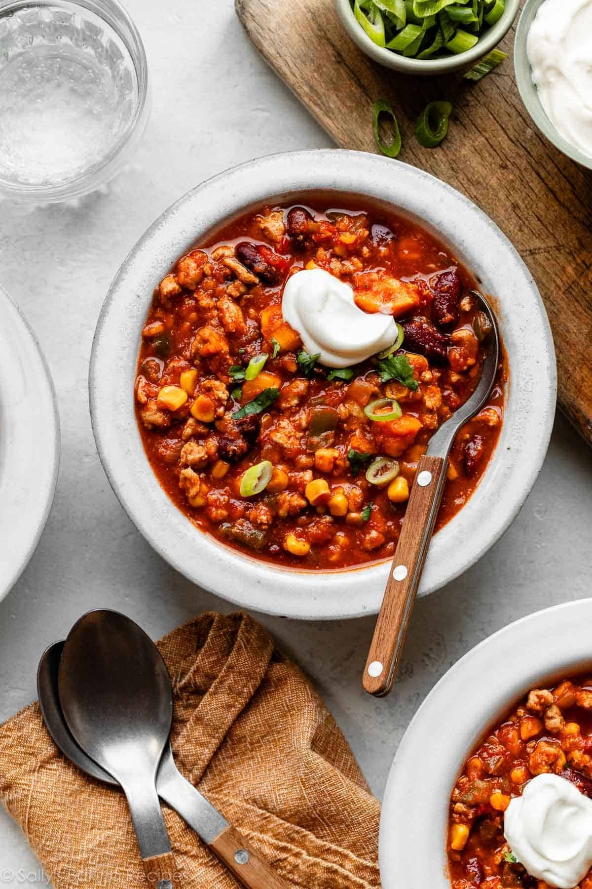 bowl of sweet potato turkey chili with spoon in it and topped with a dollop of sour cream.